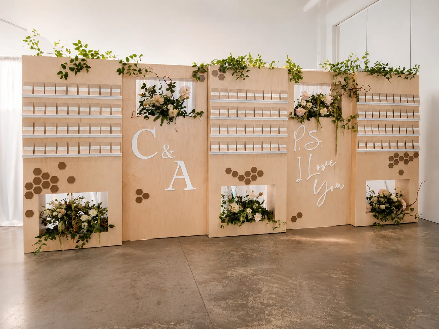 Custom architectural wedding escort card display with natural wood, greenery and floral details